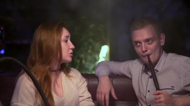 Uomo e donna comunicano nel narghilè bar. I media. L'uomo fuma narghilè mentre la donna gli parla. Socializzare e fumare nel bar narghilè — Video Stock