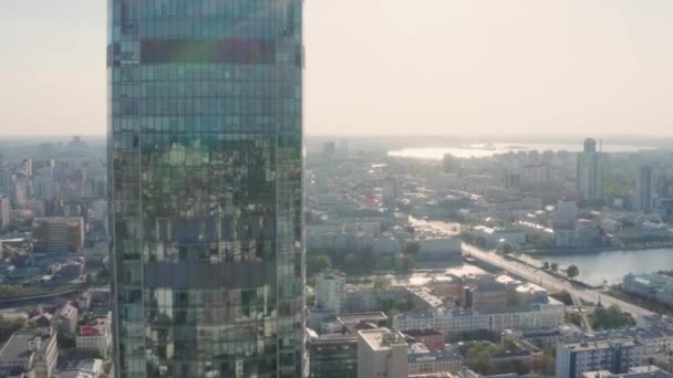 Widok z góry miasta odbity w oknach wieżowca. Materiał filmowy. Piękne odbicie miasta w szklanym wieżowcu na tle panoramy miasta w słoneczny dzień — Wideo stockowe