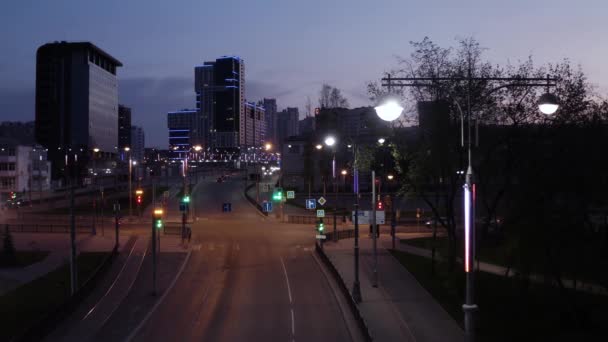 Vista superior de la autopista de la ciudad moderna con luces de neón en la noche. Imágenes de archivo. Coches raros conduciendo a lo largo de la carretera de la ciudad a la luz de luces de neón y casas en el fondo del cielo del atardecer — Vídeos de Stock