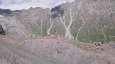 Dağcıların kar zirvesi ile kayalık dağa yürüyüşlerinin en üst görüntüsü. Şarjör. Aktif turistler karlı zirveye doğru heyecan verici dağ rotalarına çıktılar. Dağlara tırmanıyor, tırmanıyor.