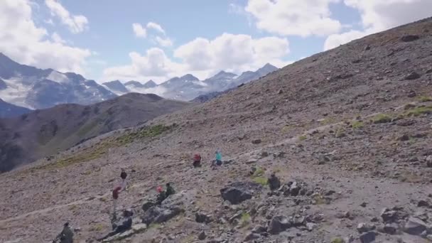 Ovanifrån av grupp turister vilar på bergsvägen. Klipp. Klättrare satte sig ner för att koppla av i bergen på bakgrund av spektakulära landskap med snötäckta toppar — Stockvideo