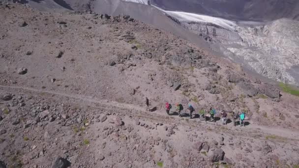 Bovenaanzicht van de groep van opklimmende toeristen op de achtergrond van het berglandschap. Een knip. Lijn van klimmers volgt bergroute op achtergrond van spectaculaire bergketens — Stockvideo