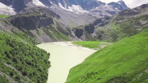 Blick von oben auf den grünen See in den Bergen. Clip. Schmelzwasser, das von den Bergen herabfließt, bildete einen See, der schließlich stagnierte und grün wurde — Stockvideo