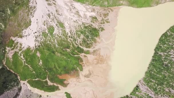 L'acqua di fusione che forma il lago in montagna. Clip. Vista dall'alto di incredibili paesaggi montani con acqua di fusione proveniente da cime innevate e formando il lago. Passo verde di montagna con lago — Video Stock