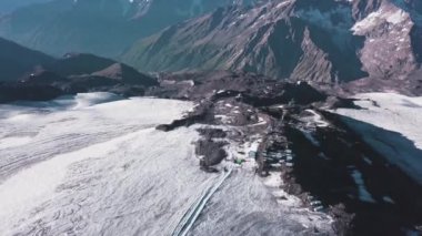 Kayalık karlı dağlardaki küçük kasaba manzarası. Şarjör. Dağcılar için yüksek kayalık dağlarda bulunan karavan evleri. Güneşli bir günde karlı dağlarda seyahat edenler için aktarma noktası