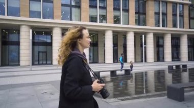 Kadın banka binasının fotoğraflarını çekiyor. Başla. Kadın fotoğrafçı şehirde dolaşıyor ve iş merkezlerinin modern mimarisinin fotoğraflarını çekiyor.
