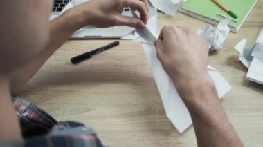Origami kağıdını katlayan adama yakın çekim. Stok görüntüleri. Erkeklerin elleri beyaz kağıt origamiden ya da uçaktan katlanır. İşte mola sırasında Origami sınıfı