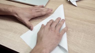 Origami kağıdını katlayan adama yakın çekim. Stok görüntüleri. Erkeklerin elleri beyaz kağıt origamiden ya da uçaktan katlanır. İşte mola sırasında Origami sınıfı