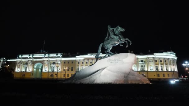 Historyczny pomnik z cesarzem na koniu w nocy. Akcja. Pomnik rosyjski cesarz stoję na kamień na tle historyczny budowla z nocny oświetlenie. Jeździec z brązu — Wideo stockowe