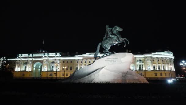 Monumento histórico con emperador a caballo por la noche. Acción. Monumento al emperador ruso se encuentra en piedra sobre el fondo del edificio histórico con iluminación nocturna. Jinete de bronce — Vídeo de stock