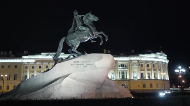 Historyczny pomnik z cesarzem na koniu w nocy. Akcja. Pomnik rosyjski cesarz stoję na kamień na tle historyczny budowla z nocny oświetlenie. Jeździec z brązu — Wideo stockowe