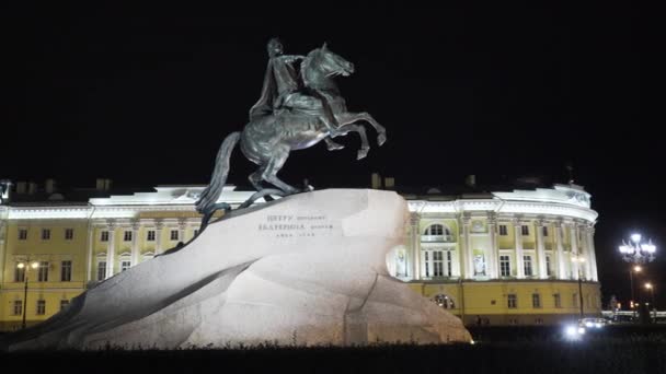 Monumento iluminado de Cavaleiro de cobre à noite. Acção. Grande monumento ao Imperador a cavalo em pé sobre pedra. Monumento famoso de São Petersburgo à noite — Vídeo de Stock