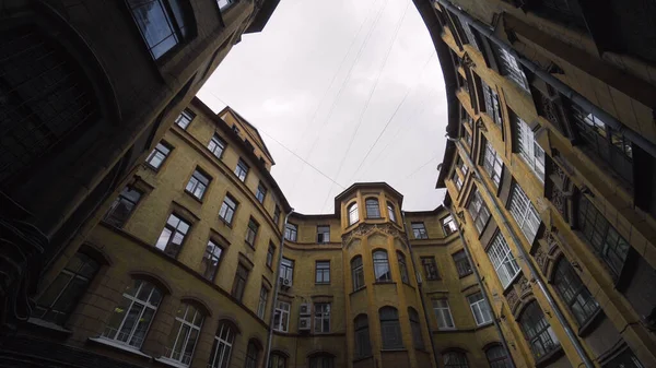 Cortile di vecchio edificio rotondo in città. Azione. Vista inferiore della vecchia casa con cortile ben sullo sfondo del cielo. Vecchi cortili chiusi di case a San Pietroburgo — Foto Stock