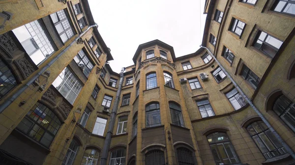 Courtyard of old round building in city. Action. Bottom view of old house with courtyard well on background of sky. Old closed courtyards of houses in St. Petersburg