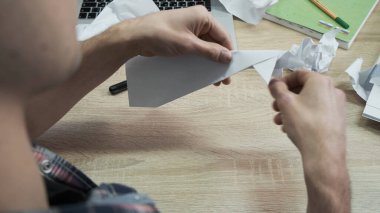 Origami kağıdını katlayan adama yakın çekim. Stok görüntüleri. Erkeklerin elleri beyaz kağıt origamiden ya da uçaktan katlanır. İşte mola sırasında Origami sınıfı