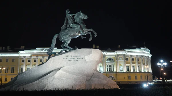 夜に馬に乗って天皇との歴史的記念碑。行動だ。ロシア皇帝への記念碑は、夜の照明と歴史的な建物の背景に石の上に立っています。青銅馬頭 — ストック写真