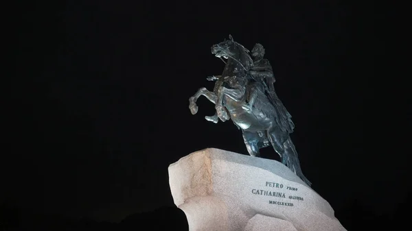 Monument à l'empereur à cheval avec éclairage sur fond de ciel nocturne. L'action. Cavalier en cuivre semble majestueux avec éclairage la nuit. Monument à Pierre sur fond de ciel noir — Photo