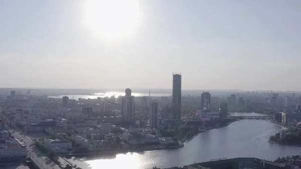 La construcción de nuevos edificios residenciales y de oficinas modernos detrás del río en un día de verano. Imágenes de archivo. Paisaje urbano de Ekaterinburg con arquitectura soviética y moderna. — Foto de Stock