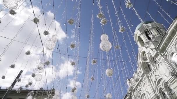 Botten bild av hängande dekorationer mot blå himmel med vita moln. Börja. Moskva, Ryssland, arkitektur Nikolskaja gatan i Moskva på solig sommarmorgon och dekorativa kransar hängande — Stockvideo