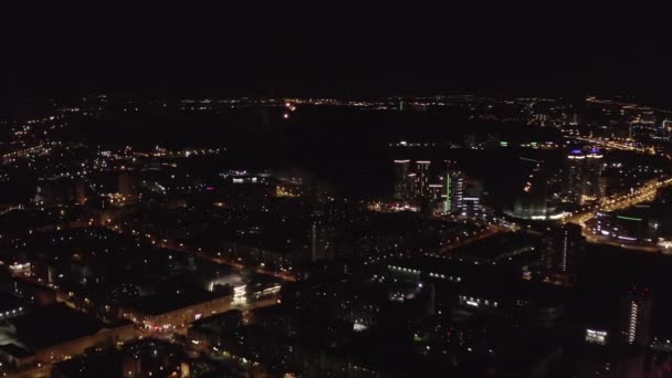 Scenic view at night of a big city with buildings in lights and fireworks. Stock footage. Aerial view of fireworks above houses on night black sky background. — Stock Video