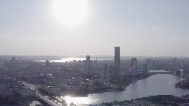 La construcción de nuevos edificios residenciales y de oficinas modernos detrás del río en un día de verano. Imágenes de archivo. Paisaje urbano de Ekaterinburg con arquitectura soviética y moderna. — Vídeos de Stock