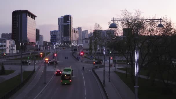 Αεροφωτογραφία της πόλης το ηλιοβασίλεμα, με διασταυρούμενα και φανάρια. Στικ. Βραδιά σε μια σύγχρονη πόλη με ψηλά κτίρια που διακοσμούνται από γυάλινα παράθυρα και λάμπες. — Αρχείο Βίντεο