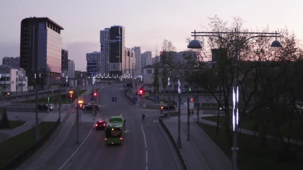 Widok z lotu ptaka na miasto o zachodzie słońca, ze światłami skrzyżowania i światłami. Materiał filmowy. Wieczór w nowoczesnym mieście z wysokimi budynkami ozdobionymi szklanymi oknami i świecącymi lampami. — Wideo stockowe