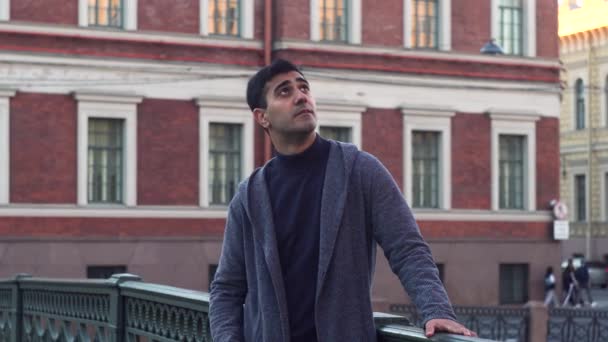 Handsome male tourist enjoing architecture. Media. Side view of carefree young man standing and thinking about something in the street on the background of driving cars. — Stock Video