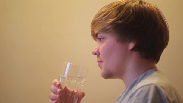 Ung uttorkad man dricker filtrerat mineralklart vatten. Begreppet. Sidovy av törstig kille som håller transparent glas och dricksvatten, hydrering och hälsa koncept. — Stockvideo