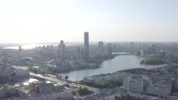 Primer plano de las ventanas de cristal de un rascacielos y el paisaje urbano detrás de él. Imágenes de archivo. Vista aérea del moderno centro de negocios y la ciudad con un río. — Vídeos de Stock