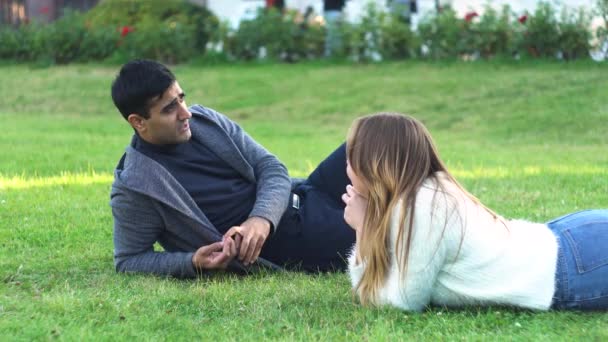 Mais perto da natureza. casal se sentir livre e deitar na grama verde no parque da cidade. Mídia. Vista lateral de homem e mulher amigos ou casal romântico relaxar ao ar livre no prado verde e bate-papo. — Vídeo de Stock