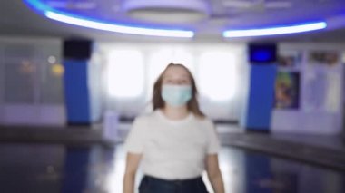 Maskeli kadın AVM 'de sıcaklığı kontrol ediliyor. Medya. Sinema ve alışveriş merkezlerini ziyaret edenler temas olmayan termometre kullanılarak sıcaklık için kontrol edilirler.