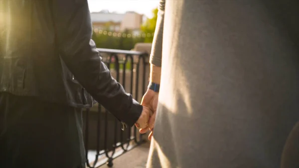 Close-up of couple in love walking in park holding hands. Action. Rear view of walking couple holding hands. Stylish couple in love romantically holding hands on walk — Stock Photo, Image