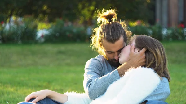 Любляча пара обіймає і цілує, сидячи на траві в парку. Поняття. Солодкий і красивий чоловік і жінка насолоджуються і проводять час разом . — стокове фото