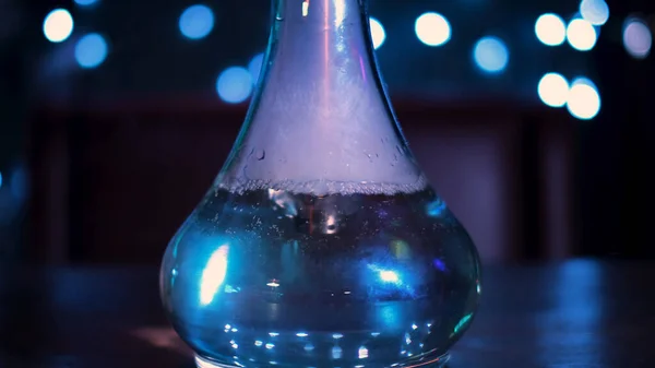 Fumar narguilé na mesa escura no fundo luzes azuis. Mídia. Frasco de narguilé de vidro com líquido transparente na sala escura de um bar ou restaurante. — Fotografia de Stock