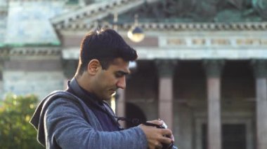 Granit sütunlu bir tapınağın arka planında günlük kıyafetli bir gezginin yan görüntüsü. Medya. Şehir sokağındaki eski bir binanın önünde kameraya bakan erkek turist..
