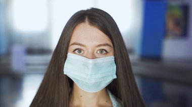 Kadın girişte maske takıyor. Medya. Güzel genç bir kadın alışveriş merkezinde ya da sinemada maske takar. Alışveriş merkezi ve sinemayı ziyaret ederken koruyucu maskeler gereklidir