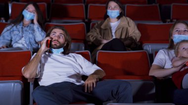 Sinemada telefonla konuşan genç bir adam. Medya. Küstah adam sinemada telefonla konuşuyor ve film izlemeye engel oluyor. Koronavirüs salgını sırasında sinemaya gitmek