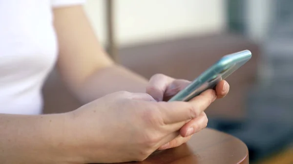 Gros plan d'une femme tapant au téléphone. Les médias. La femme utilise le téléphone dans la rue. Smartphone tactile moderne dans les mains de la jeune femme — Photo