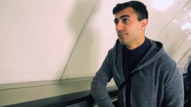 Metroda yürüyen merdivende duran genç bir adamın portresi. Medya. Yürüyen merdivenden çıkan adam sıkılmış görünüyor. Yeraltı taşımacılığı kavramı..