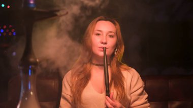 Gece kulübünde doğal makyajlı güzel, seksi genç bir kadın. Medya. Barda nefes alıp veren ve doğrudan kameraya bakan bir kadın..