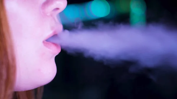 Close up de lábios liberando fumaça vape de e-cigarro ou narguilé no fundo escuro. Mídia. Detalhes de cara de uma mulher caucasiana lábios exalando shisha fumaça. — Fotografia de Stock