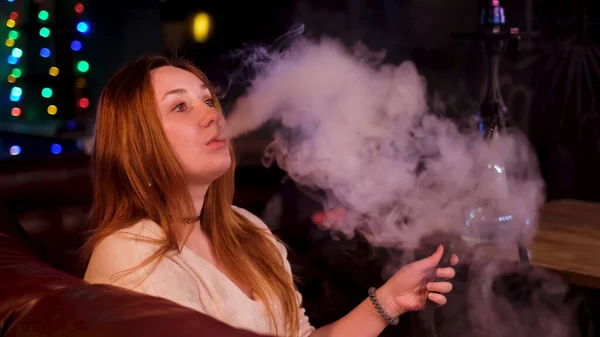 Γυναίκα καπνίστρια με ναργιλέ σε σκούρο φόντο του εσωτερικού κλαμπ. Μέσα ενημέρωσης. Συν μέγεθος όμορφο μοντέλο με μια κακή συνήθεια του καπνίσματος shisha, έννοια της αναψυχής και να χαλαρώσετε. — Φωτογραφία Αρχείου