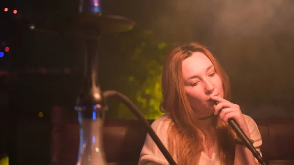 Close-up portret van een jonge bruinharige vrouw sexy roken hookah op een donkere achtergrond. De media. Charmant eenzaam pensive meisje roken shisha aan de bar. — Stockfoto