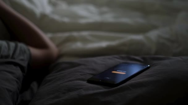 Nahaufnahme eines schlafenden Mannes, der von seinem Handy geweckt wird, das auf dem Bett liegt. Konzept. Männliche Hand versucht, den Wecker auszuschalten, der in der Nähe auf einer Decke zu Hause in den frühen Morgenstunden liegt. — Stockvideo