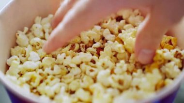 Erkek eli, kovadan patlamış mısır alıyor. Sinema konsepti. Medya. Koyu mavi bir kaseden lezzetli patlamış mısır alan bir adam eli..