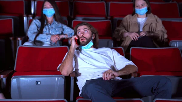 Ten chlap mluví po telefonu a otravuje lidi v kině. Média. Mladá žena žádá zastavit druhého muže mluvit do mobilního telefonu při sledování filmu v kině. — Stock fotografie