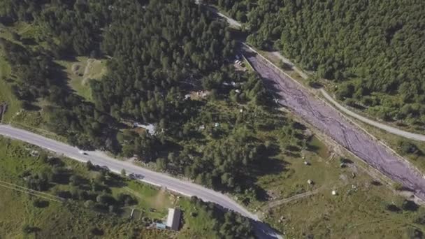 Luchtfoto van de landweg en het bos in de zomer. Een knip. Top uitzicht op prachtige zomer bergen vallei met groeiende pijnbomen en een auto. — Stockvideo