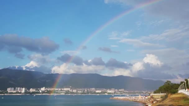Vista mozzafiato dell'arcobaleno tocca il mare durante la pioggia in una piccola città sul Mar Nero. Concetto. Estate paesaggio marino su sfondo cielo nuvoloso blu. — Video Stock