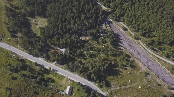 Vista aérea de la carretera rural y el bosque en verano. Clip. Vista superior del hermoso valle de las montañas de verano con pinos en crecimiento y un coche de conducción. — Foto de Stock